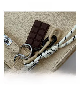 Detail of beige lychee leather bag with chocolate pendant and acrylic chain