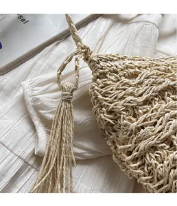 Detailed view of beige hand-woven straw bag featuring stylish long tassel decorative fringe