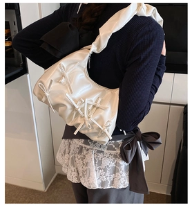 Detail view of cream pleated shoulder bag with 3D bow accents and soft texture