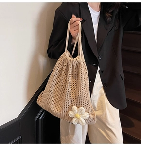 Close-up of beige hollow knit tote bag with a 3D daisy flower charm detail
