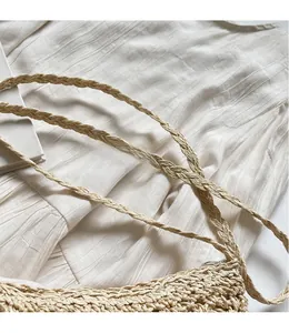 Detailed macro view of handcrafted woven straw bag texture with a long shoulder strap