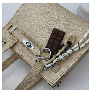 Detail of lychee pattern leather handbag with silver twist lock and chocolate charm