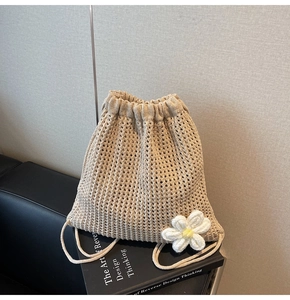Detail shot of beige crochet drawstring bag with floral accent on a minimalist background