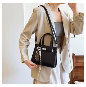 Detail of black pebbled leather handbag with silver twist lock and woven strap decoration