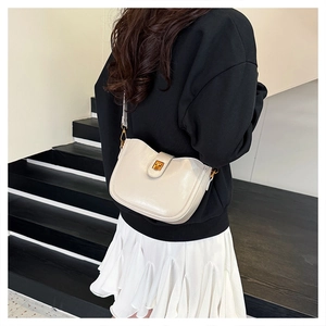 Detail der cremefarbenen Halbmond-Tasche mit goldener Schnalle an einem Model