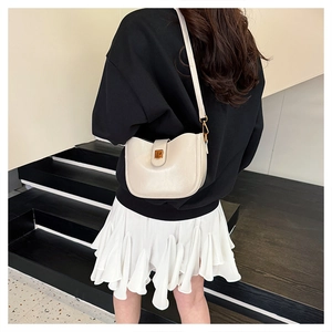 Schicke cremefarbene Beuteltasche am Model mit elegantem Goldverschluss und Riemen