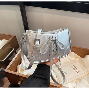 Silberne Metallic-Handtasche mit Schleife auf weißem Seidenstoff mit Trageriemen-Detail
