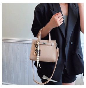 Detail of beige lychee leather handbag with metal twist lock and fashion accessory straps