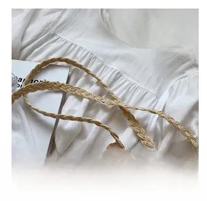 Détail de la bandoulière en paille tressée et texture ajourée sur le sac d'été