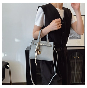 Close-up of light grey litchi texture handbag with silk scarf and gold lock detail