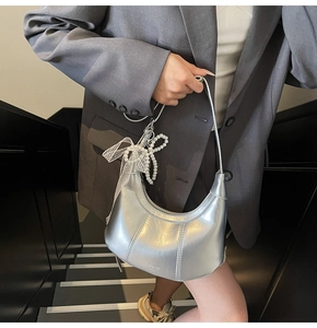 Detail of silver metallic hobo bag with white lace bow and pearl pendant charm