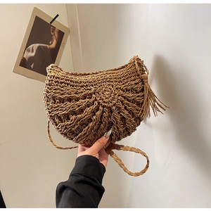 Close-up of hand-woven straw bag featuring unique radial texture and stylish side tassels