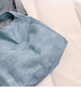 Detail of light blue denim tote bag featuring sparkling silver rhinestones and soft texture