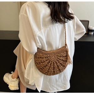 Detail of woven straw crossbody bag with radial texture and tassel on a model