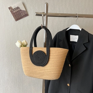 Fashionable woven straw tote bag with black rope handles and circular pattern design