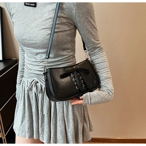 Detailansicht der schwarzen Leder-Baguette-Tasche mit Satinschleife und Schnürung