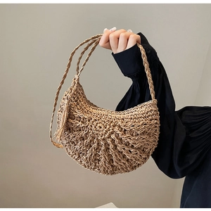 Close-up of hand-woven straw bag with fringe detail and long shoulder straps