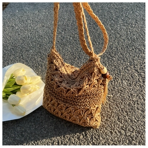 Detail einer handgewebten Strohtasche mit Blumenmustern und Quasten aus Holzperlen