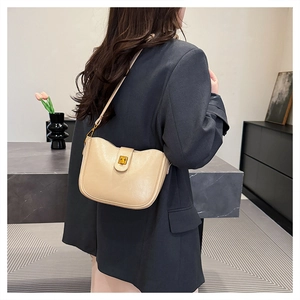 Detail der cremefarbenen Vintage-Tasche mit Goldschnalle auf grauem Blazer-Outfit