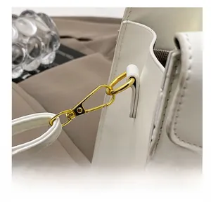 Close-up of premium gold-toned metal hook and stitching details on a white leather handbag