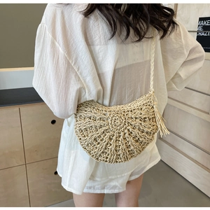 Detail of bohemian straw crossbody bag with hollow weave and tassel on shoulder
