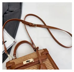 Detail of the woven straw and brown leather handle with gold-tone hardware and strap
