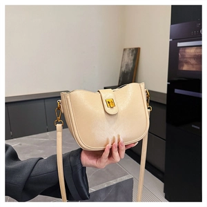 Detail der cremefarbenen Lackleder-Beuteltasche mit goldener Schnalle und Gurt