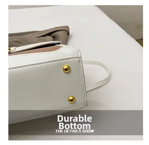 Macro view of white faux crocodile leather bag with golden metal protective feet