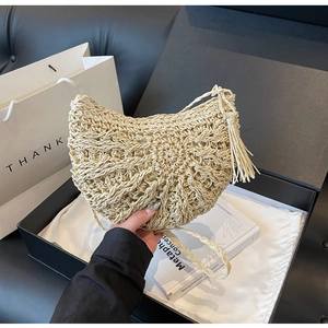 Detail of hand-woven beige straw shoulder bag with stylish tassel and crescent moon shape
