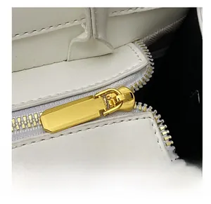 Close-up of golden metal zipper on a white crocodile pattern handbag with neat stitching