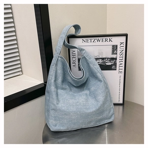 Detail of light blue denim hobo bag with sparkling rhinestones on a metal table