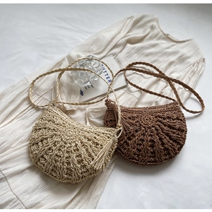 Detailed shot of handmade crochet crescent crossbody bag with long tassel fringe and woven strap