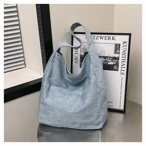 Detail of light blue textured canvas tote bag featuring a wide shoulder strap design