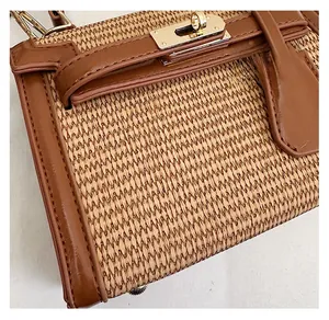 Close-up of woven raffia texture and brown leather flap with gold-tone twist lock detail