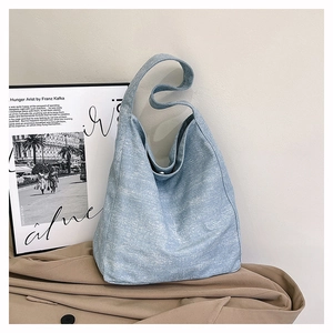 Detail shot of light blue canvas hobo bag with snowflake texture on stylish trench coat