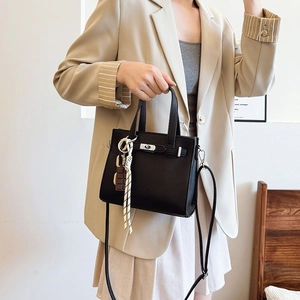 Classic black lychee leather handbag with silver lock shown in lifestyle fashion setting