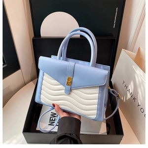Blue and white quilted handbag with gold clasp presented in a luxury black gift box