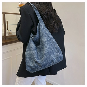Detailed view of a navy blue textured canvas tote bag worn on shoulder in a cafe setting