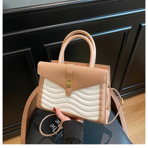Detail of nude and white stitched bag with wave quilting and gold turn-lock closure