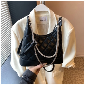 Detail of black quilted shoulder bag featuring silver dual chains and PU leather texture