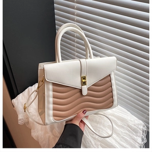 Detailed view of bicolor wave-stitched texture and gold twist lock on women's handbag