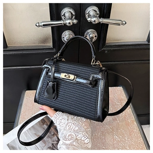 Close-up of black woven Kelly bag with glossy leather trim and gold twist-lock hardware