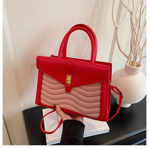 Macro detail of red and pink contrast handbag with wavy stitching and gold twist lock