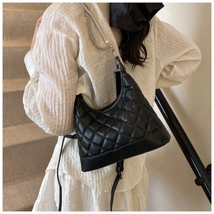 Rear view of a black quilted hobo bag with a silver chain strap and pearl detail