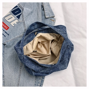 Detail of blue denim tote bag showing spacious interior with zipper pocket and magnetic clasp