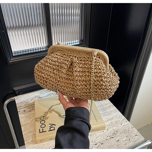 Détail de la pochette en paille tressée kaki avec chaîne dorée et fermoir vintage