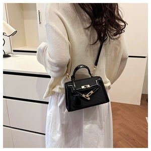 Detail of black Kelly style handbag with woven texture and gold twist lock clasp
