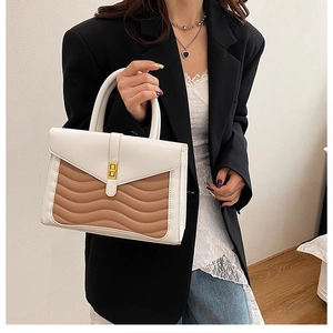 Detail of color-block tote with white top handle and khaki wavy quilted pattern