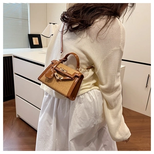Detail of woven straw and brown leather contrast on a modern crossbody Kelly bag