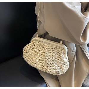 Détail du sac nuage en paille tressée beige avec bandoulière chaîne dorée élégante